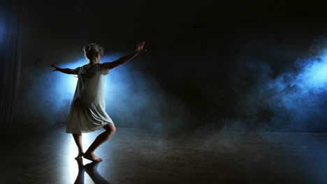 Una-Mujer-Vestida-De-Blanco-Baila-En-El-Escenario-Las-Dramáticas-Danzas-Del-Ballet-Moderno.-Una-Bailarina-De-Ballet-Mueve-Plástico-Realizando-Coreografías-Modernas-En-Humo.